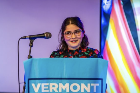 A picture of a young woman with glasses at a podium